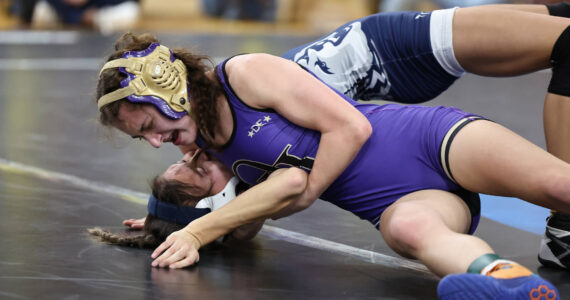 Oak Harbor’s Julia Gonzales tries to pin her opponent during the subregional tournament that took place last weekend at Oak Harbor High School. Gonzales placed first at 100 pounds and the Wildcats won the tournament. (Photo by John Fisken)