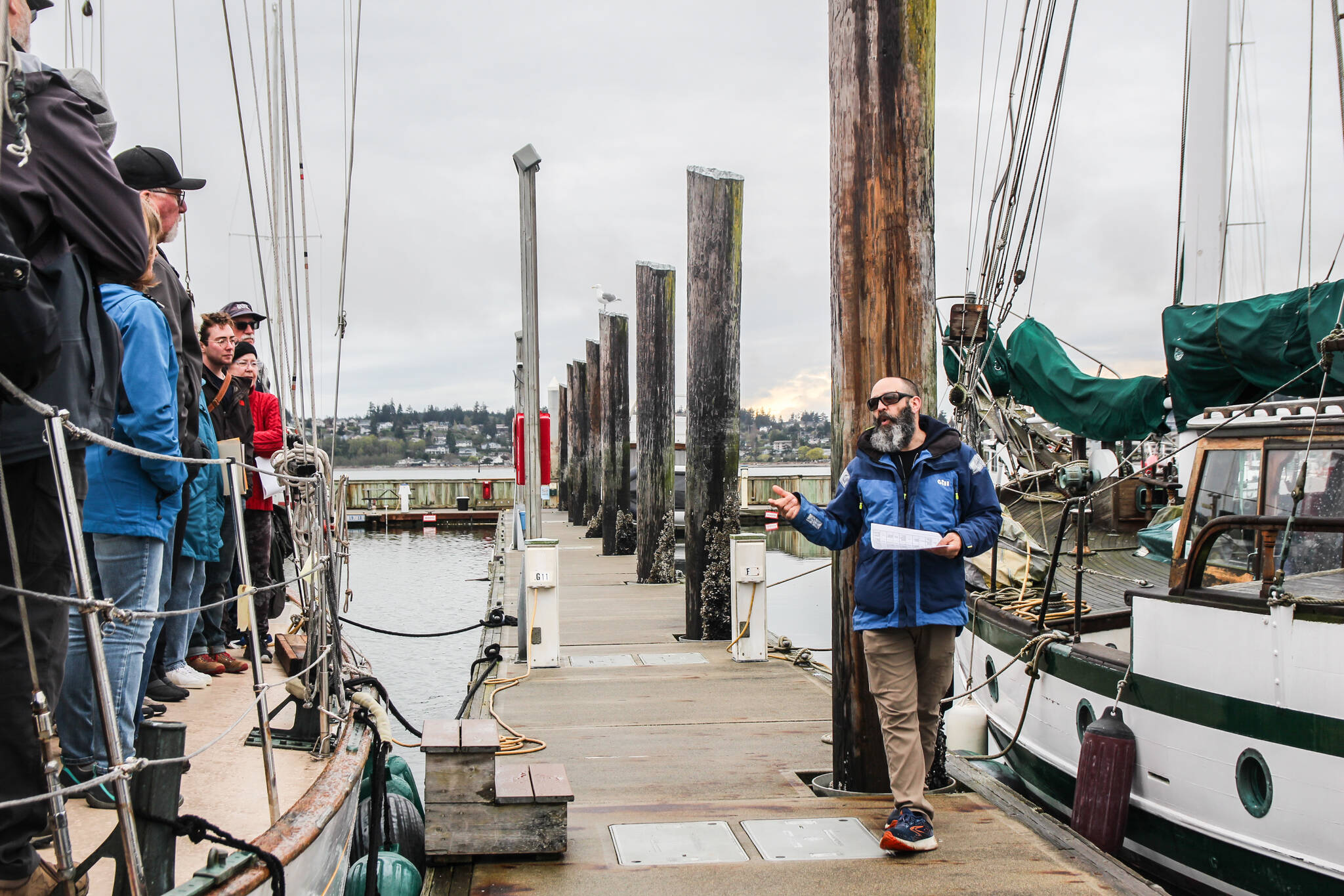 (Photo by Luisa Loi)
Captain Brian Vick, at right, explained a group of volunteers in training, at left, how to respond to emergency situations. The group met at the Oak Harbor Marina, where Suva will stay until it sails to Penn Cove on April 25.