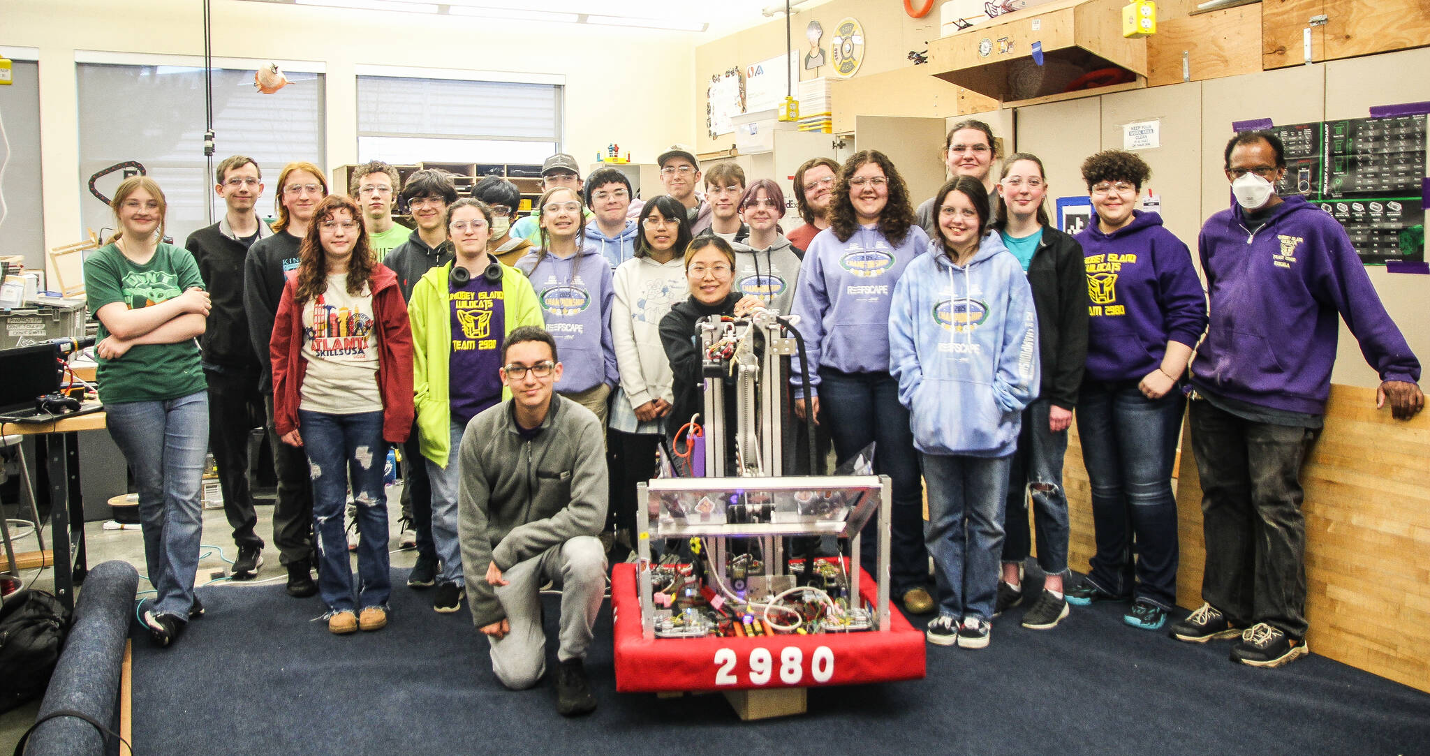 Some members of team 2980 pose for a photo with Evb0t. Most of the following students are from Oak Harbor, as their Coupeville teammates had class. At left, Bella McGinty, Mentor Logan Ince, Orion Liedtke, Emerald Papke, Joshua Lemon, Tyler Sika, Poyo Hutchinson, Nico Olalia, Tristan Nuanez, Thorin Allen, Masyn Eberhardy, Joshua Beltran, Michi Rosas Abarca, James Gazy, Elena Lin, Temur Pedde, Natalie Perera, Gabe Smith, Allena Locklear, Elizabeth Eberhardy, Gideon Odeneal, Valerie Gerdes, Isabelle Locklear and Mentor Che Edoga. (Photo by Luisa Loi)