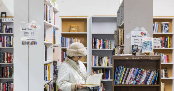 A woman flips through a book at the Good Cheer Thrift Store in Langley. (Olivia Vanni / The Herald)