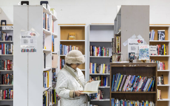 A woman flips through a book at the Good Cheer Thrift Store in Langley. (Olivia Vanni / The Herald)