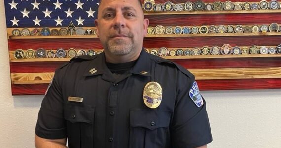 Captain Kevin Barton stands in front of an artistic rendering of the United States flag after getting onboarded to the Oak Harbor Police Department last June (Photo by Jessie Stensland)