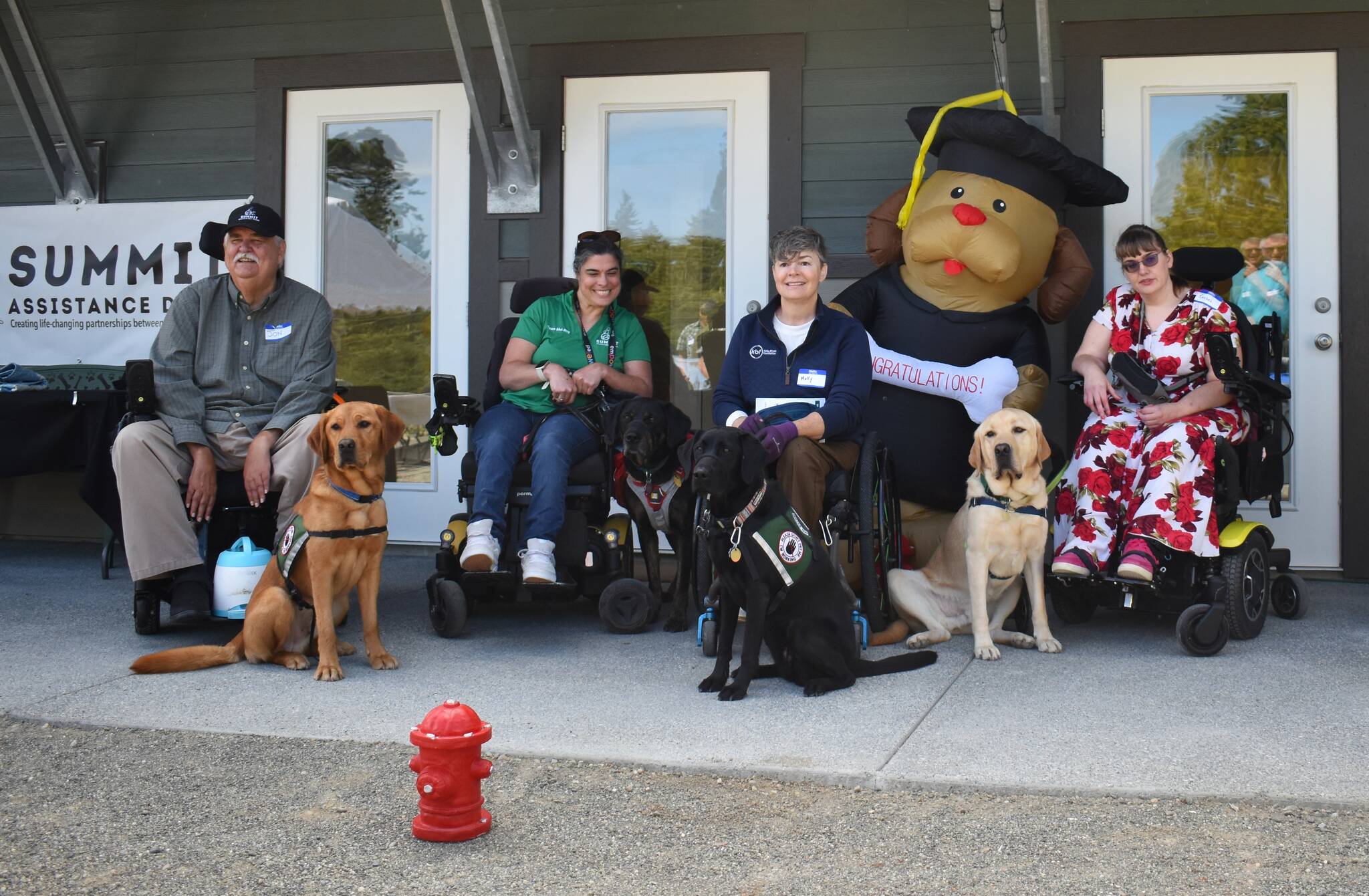 (Photo by Emily Gilbert) Graduates - both human and canine - pose for a photo in front of Summit Assistance Dogs’ new facility on Jones Road in North Whidbey named “Chris’ Canine Condo.”