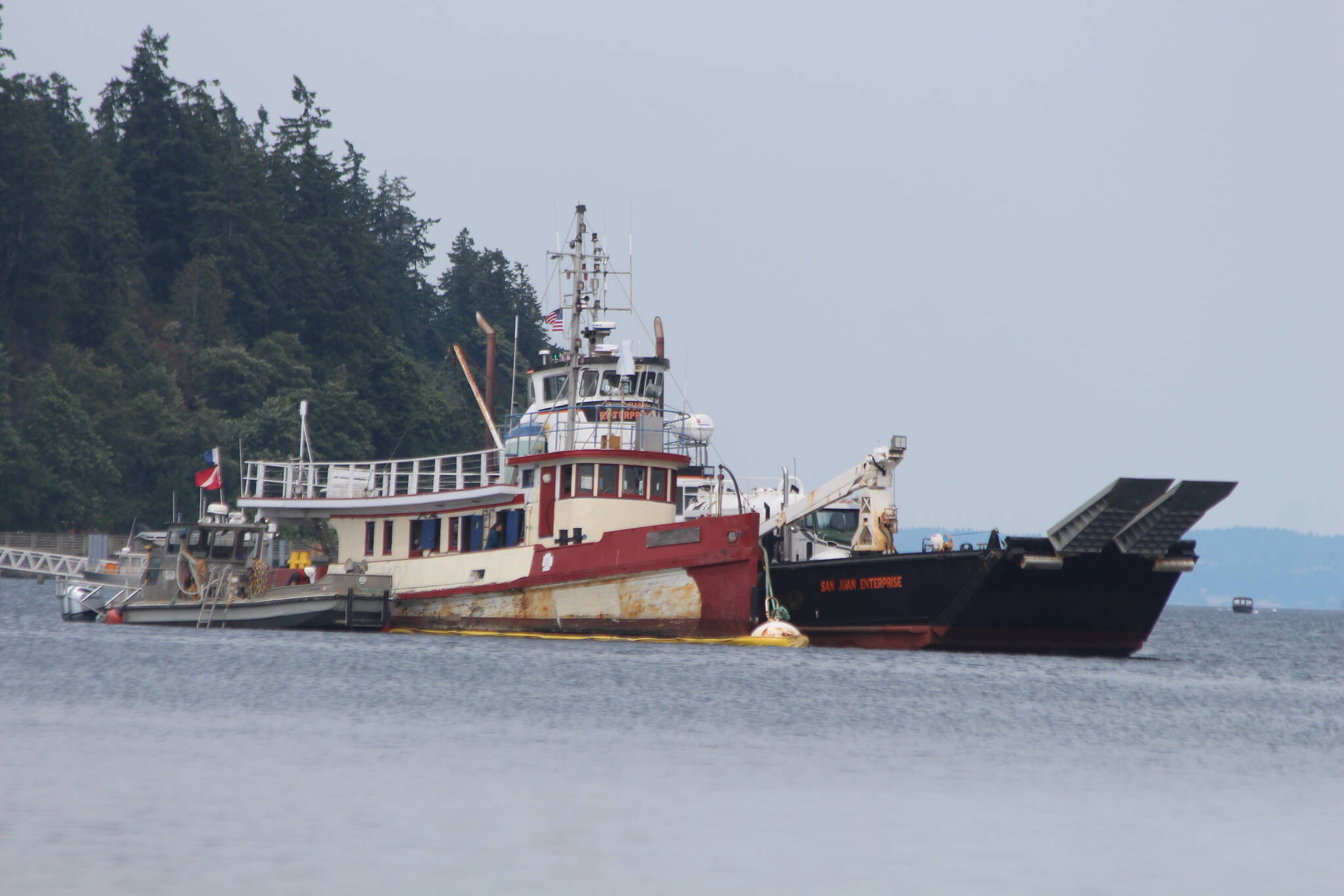 (Photo by Marina Blatt) The sinking Shark Lady is sandwiched between a hazmat rescue vessel on the left, and the San Juan Enterprise, on the right, which is certified by the U.S. Coast Guard to legally haul flammable liquids, according to its website.