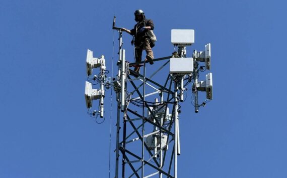 Astound technician installing fixed wireless network transmission devices atop existing headend tower.